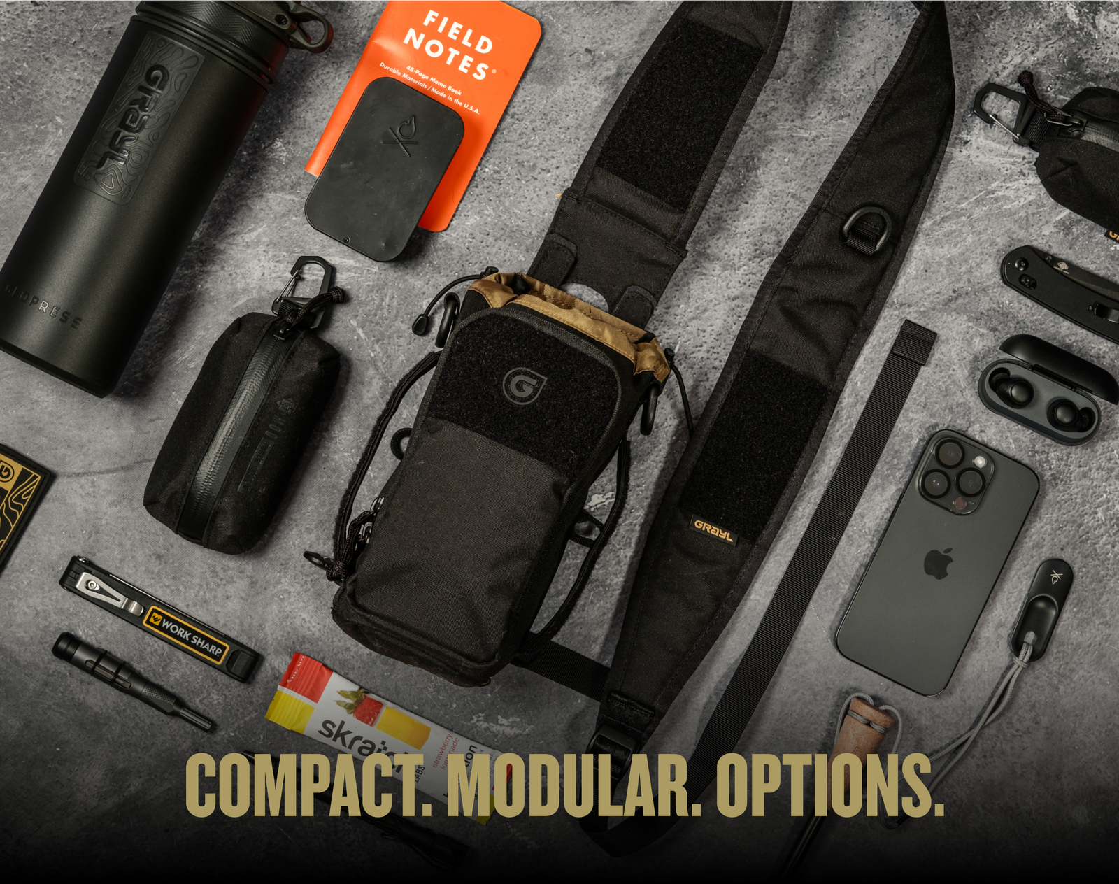 Flat lay photo of Transport Bottle Carrier in Covert Black colorway. Pictured along common contents that can be careered within the complete modular system. Iphone, flashlight, knife, blade sharpener, pen, water bottle, Grayl, Field notes journal.