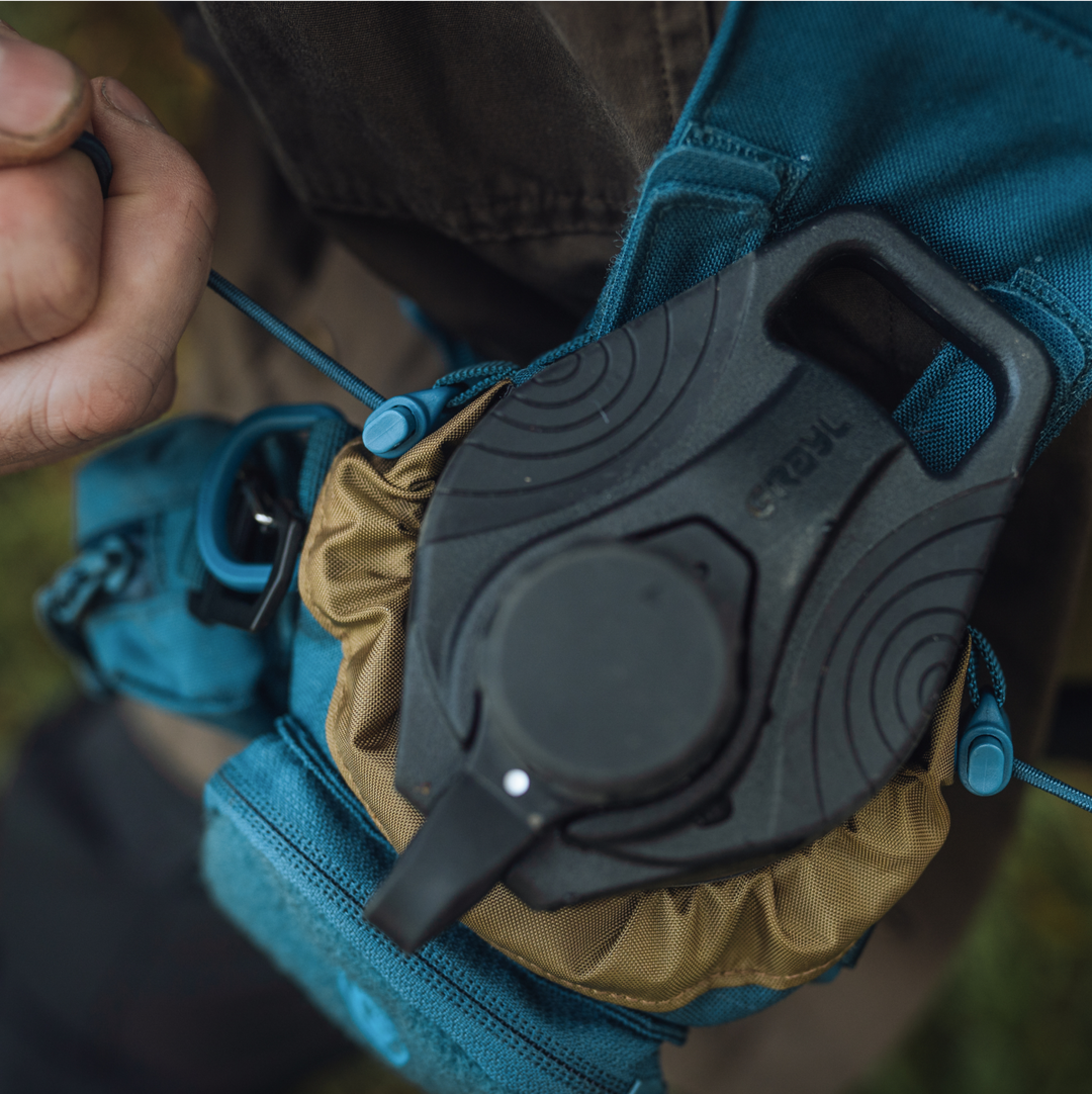 GeoPress Water Filter Purifier Bottle picture in Grayl Transport Bottle Sling being secured by hiker with dual-sided cinch closure top.