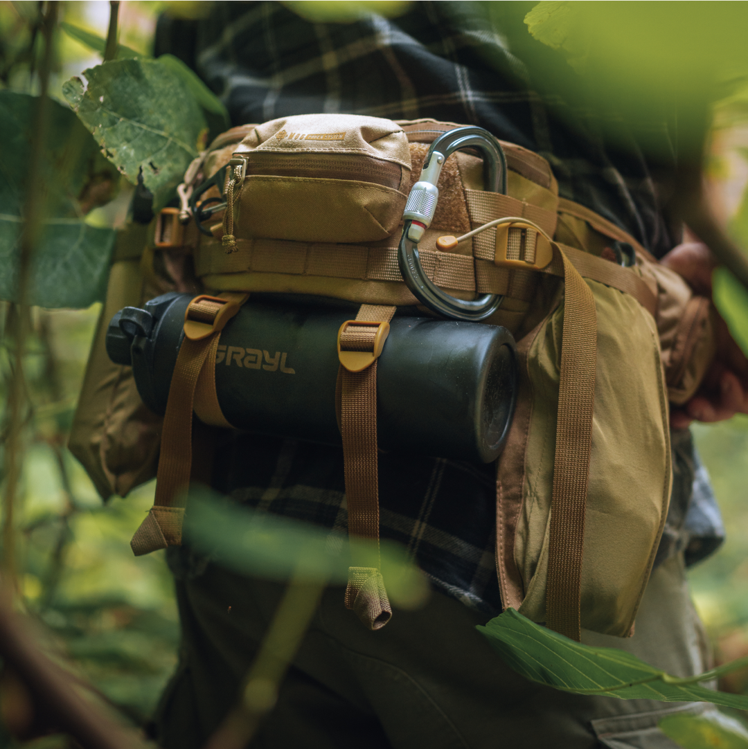 Grayl® GeoPress Titanium "Black Edition" suspended in BottleLock® Tie Downs on the 2L Mission Hip Pack. Hiker located deep in the forest canopy.