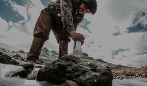 Man in mountains using a Grayl Geopress water filter.